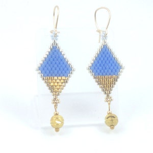 Puede incluir: Un par de pendientes de cuentas azules y doradas con forma de diamante y una cuenta dorada en la parte inferior.