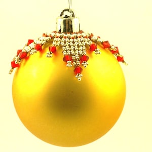 May include: A gold Christmas bauble with a red and gold beaded trim.