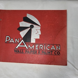 May include: A red cover with a black and silver stylized Native American headdress. The text "Pan-American Wall Paper & Paint Co." is printed in black.