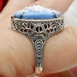 May include: A silver ring with a blue and white cameo set in a filigree design.