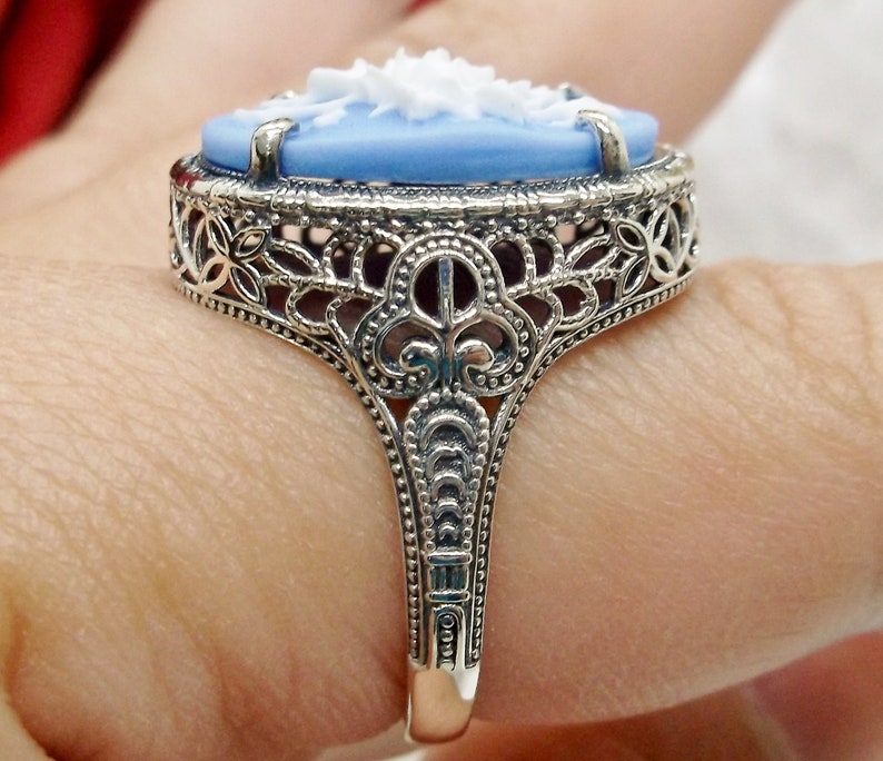 May include: A silver ring with a blue and white cameo set in a filigree design.