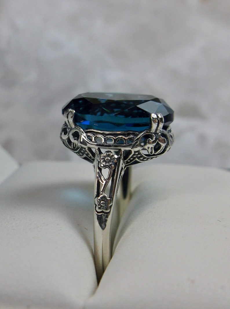May include: A silver ring with a large, dark blue gemstone set in a filigree design.