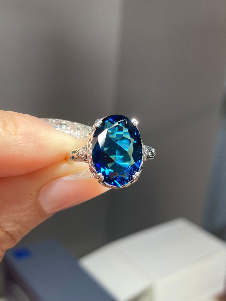 May include: A silver ring with a large oval-shaped blue gemstone set in a decorative silver band.