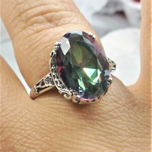 May include: A silver ring with an oval-shaped, iridescent gemstone. The gemstone has shades of green, blue, and purple.