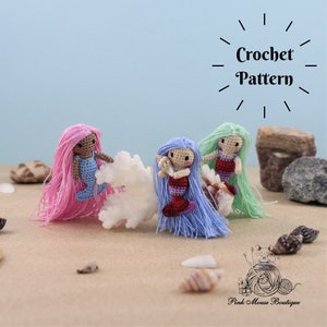 Puede incluir: Tres muñecas de sirena de crochet con cabello largo en rosa, azul y verde. Las muñecas están sentadas en un arrecife de coral blanco con conchas esparcidas alrededor. El texto "Crochet Pattern" está escrito en negro sobre un fondo blanco.