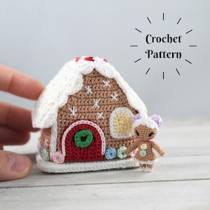 May include: Crocheted gingerbread house with white icing and sprinkles, a red door with a green wreath, and a small gingerbread person standing next to it. "Crochet Pattern" is written above the house.