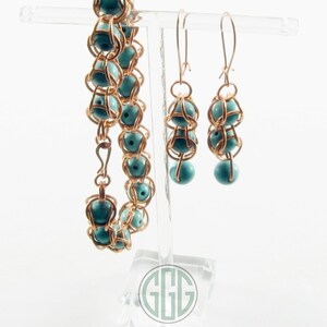 May include: A set of turquoise and gold jewelry featuring a bracelet and a pair of earrings. The bracelet and earrings are made with wire wrapped around turquoise beads.