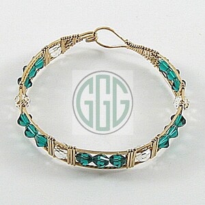 May include: A gold wire wrapped bracelet with emerald green and clear glass beads.