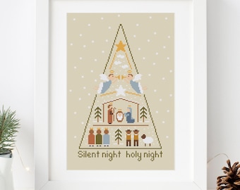 May include: A framed cross-stitch design featuring a Christmas tree with a nativity scene inside. The tree is decorated with a star and snowflakes. The text "Silent night holy night" is at the bottom of the design.