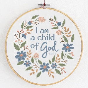 May include: A white embroidery hoop with a floral wreath design and the text "I am a child of God John 1:12".