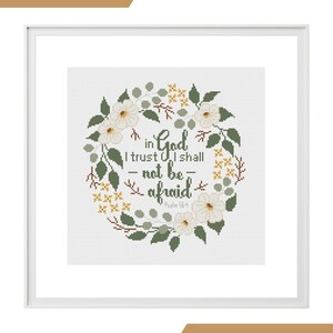 May include: Cross stitch pattern framed in white. The design features a floral wreath with white flowers, green leaves, and yellow accents. The text reads "in God I trust I shall not be afraid" with "Psalm 56:4" below. The words "PDF pattern" and "cross stitch" are also present.