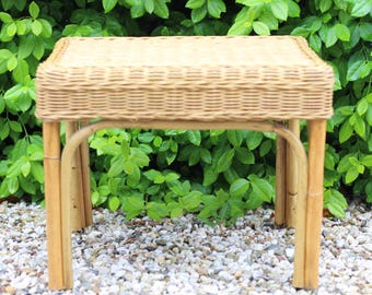 Peut inclure: Une petite table en osier naturel avec un plateau tissé et quatre pieds. La table est posée sur un lit de gravier blanc.