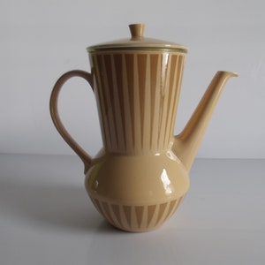 Może przedstawiać: Ceramiczny dzbanek do kawy w kolorze beżowym z paskowanym wzorem. Dzbanek ma pokrywkę i uchwyt.