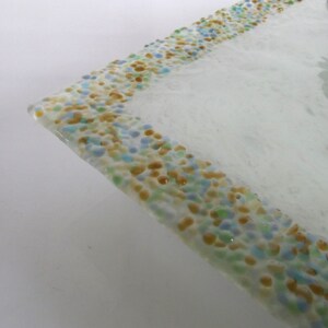 May include: A white glass serving tray with a decorative border of small, colorful glass pieces in shades of blue, green, and yellow.