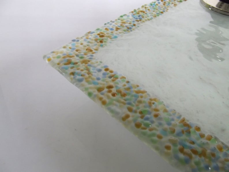 May include: A white glass serving tray with a decorative border of small, colorful glass pieces in shades of blue, green, and yellow.
