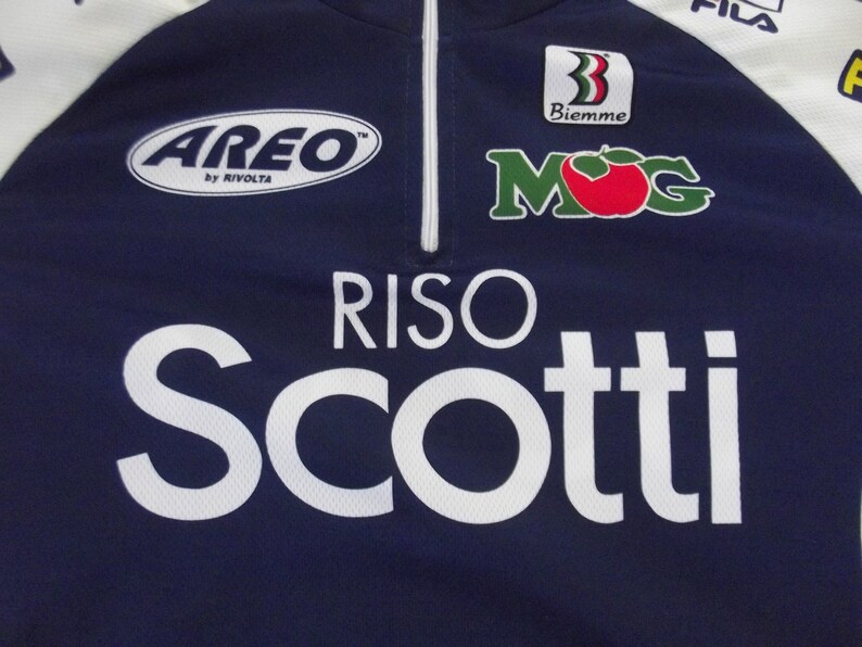 May include: A navy blue cycling jersey with white accents and sponsors' logos, including "Areo by Rivoita", "Biemme", "MOG", and "Riso Scotti".