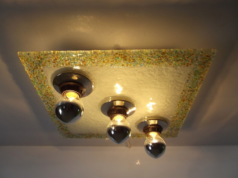 May include: A square ceiling light fixture with a frosted glass shade. The shade has a decorative border of small, colorful glass beads. The light fixture has three exposed bulbs.
