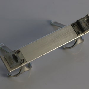 May include: A silver metal coat rack with two hooks on each end. The rack is designed to be mounted on a wall.
