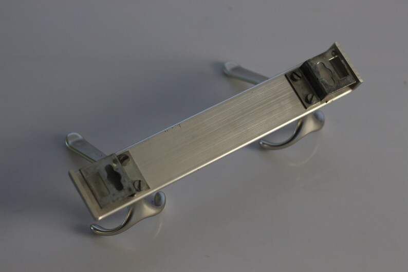 May include: A silver metal coat rack with two hooks on each end. The rack is designed to be mounted on a wall.