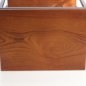 Puede incluir: Primer plano de la parte inferior de una mesa de caf&eacute; de madera con veta de madera marr&oacute;n oscuro. La mesa tiene un marco de metal negro.