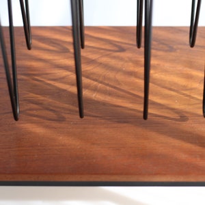 Puede incluir: Un estante de madera con soportes de metal negro. El estante est&aacute; hecho de madera oscura con un patr&oacute;n de veta natural.