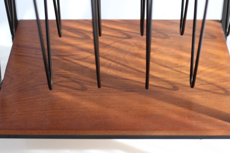 Puede incluir: Un estante de madera con soportes de metal negro. El estante est&aacute; hecho de madera oscura con un patr&oacute;n de veta natural.
