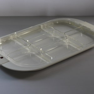 May include: A clear, divided serving tray with a white base. The tray has multiple compartments of varying sizes, ideal for serving snacks or appetizers. The design is modern and functional, suitable for entertaining.
