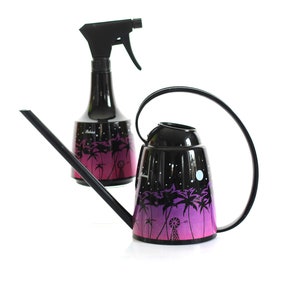 Puede incluir: Juego de regadera y pulverizador negros. El juego presenta un diseño de palmeras y molinos de viento con un degradado de morado y rosa. La regadera tiene un asa curva y un pico largo. El pulverizador tiene un gatillo negro.