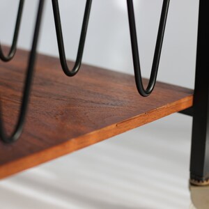 Puede incluir: Primer plano de un estante de madera con soportes de metal negro. El estante tiene una veta de madera natural y est&aacute; sostenido por un marco de metal negro.