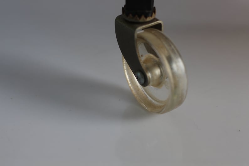 Puede incluir: Primer plano de una rueda giratoria plateada con una llanta de pl&aacute;stico transparente. La rueda est&aacute; unida a un marco de metal.