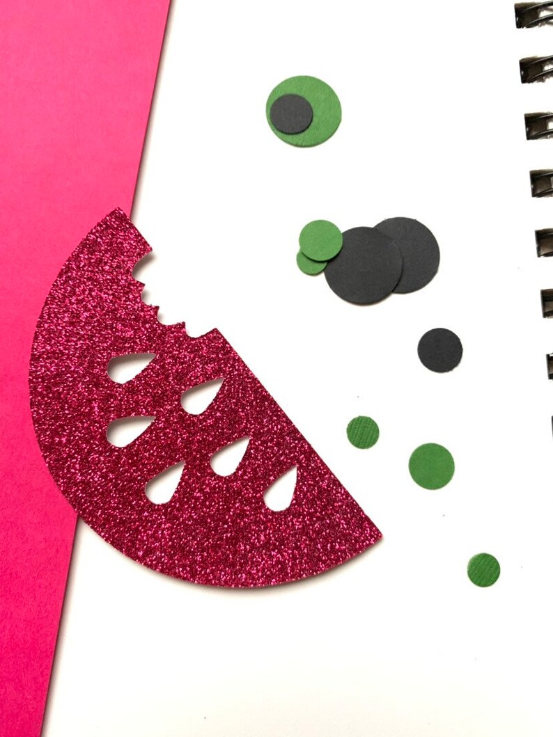 Op de afbeelding: Een glinsterende rode watermeloen schijf met een hap eruit, samen met groene en zwarte cirkelvormige vormen, mogelijk zaden en ogen. Het ontwerp staat op een witte achtergrond met een roze papieren rand.