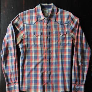 May include: A long-sleeved plaid shirt with a button-down collar and two chest pockets. The shirt is blue, red, and white.