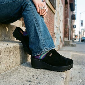 May include: A white ceramic mug with a black handle and the text "But First, Coffee" in a black, handwritten-style font. The mug is on a white surface.