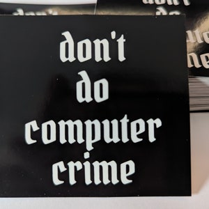 May include: Black square sticker with white text that reads "don't do computer crime" in a gothic font.