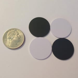 May include: Four round circles, two black and two white, arranged in a square pattern. The circles are about the size of a US quarter.