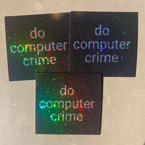 Op de afbeelding: Drie zwarte vierkante stickers met iriserende glitter. Elke sticker zegt "do computer crime" in witte tekst.