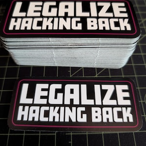 Puede incluir: Una pila de pegatinas rectangulares con el texto "LEGALIZE HACKING BACK" en blanco, delineado en rosa, sobre un fondo negro. Una pegatina se muestra por separado. Las pegatinas están apiladas.