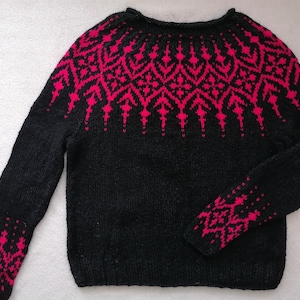 Könnte beinhalten: Schwarzer Strickpullover mit einem pinkfarbenen geometrischen Muster um den Halsausschnitt und die Ärmelbündchen.