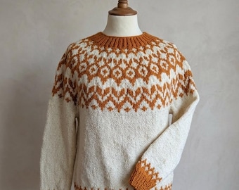 May include: A cream-colored sweater with a geometric pattern in shades of brown. The sweater features a crew neck, long sleeves, and ribbed cuffs and hem. The pattern is repeated on the yoke and cuffs. The sweater is displayed on a mannequin.