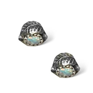 Puede incluir: Un par de pendientes de plata con un diseño de hoja y una pequeña piedra de ópalo en el centro.