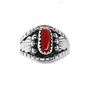 Könnte beinhalten: Ein silberner Ring mit einem roten Korallen-Stein, der in einem detaillierten Design eingefasst ist. Der Ring hat eine strukturierte Band und komplizierte Details um den Stein herum.