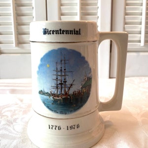 May include: White ceramic beer stein with a blue and white illustration of a ship and the text "The Boston Tea Party - C. Steamer" and "Bicentennial 1776 - 1976".