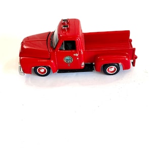 May include: Red toy pickup truck with a black bed and a white and green logo that says "Santa Clara County Fire Dept." on the side.