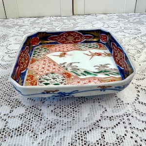 May include: A square ceramic tray with a colorful Japanese design. The tray features a blue, red, gold, and green floral pattern with waves and birds.