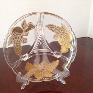 May include: A clear glass divided serving dish with three sections. Each section has a gold-colored design of grapes and leaves.