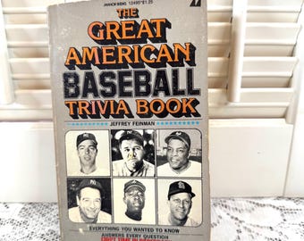 Może przedstawiać: Zabytkowa książka w miękkiej oprawie zatytułowana "The Great American Baseball Trivia Book". Okładka ma szare tło z pomarańczowym i czarnym tekstem oraz sześć czarno-białych portretów graczy baseballu. Tekst książki zawiera "Everything You Wanted to Know" i "First Time in Paperback."