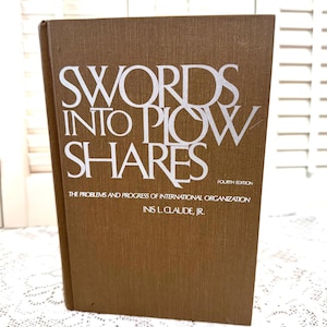 May include: A brown book with the title "Swords Into Plowshares: The Problems and Progress of International Organization" by Inis L. Claude, Jr.  The book is a fourth edition.