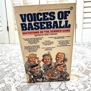 May include: A vintage paperback book titled "Voices of Baseball: Quotations on the Summer Game" edited by Bob Cheeger. The cover features a cartoon illustration of eight baseball players, including Dizzy Dean, Yogi Berra, Willie Mays, and Ron Luciano.