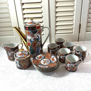 May include: A vintage tea set with a peacock design. The set includes a teapot, creamer, sugar bowl, six cups, and six saucers. The porcelain is white with gold accents and features a colorful peacock design.