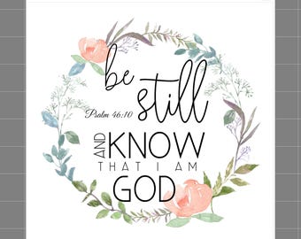 May include: A white fabric panel featuring a watercolor floral wreath in shades of peach and green. The text reads: be still Psalm 46:10 AND KNOW THAT I AM GOD. The top margin includes the text SaphiesFabrics.com 100% Cotton and a small cat icon.